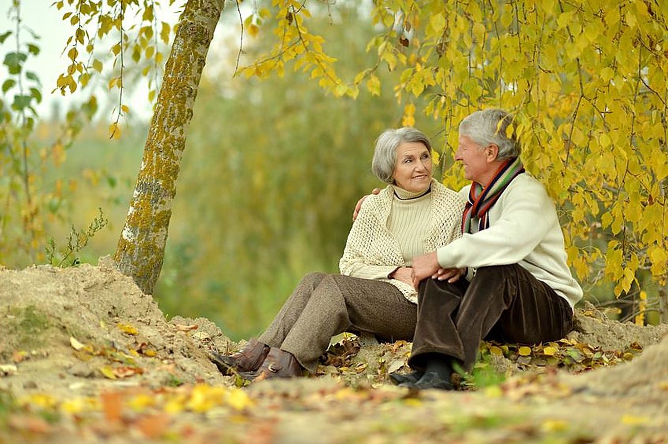 An older couple sitting together and talking in an autumn park